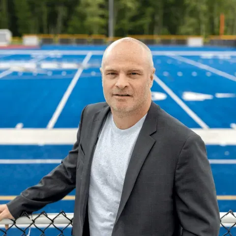 Portrait of Norm O'Reilly with the UNE football field in the background